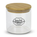A large round glass storage canister with a bamboo lid and a decorative logo on the front.