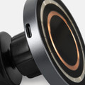 A wireless car charger in black and metallic silver, featuring a circular design and a charging port.