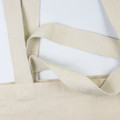 A beige tote bag with textured straps and a simple design, featuring a logo.