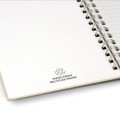A recycled paper spiral notebook with a white cover and a silver spiral binding, featuring a recycling symbol.