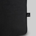 A black tote bag with a textured surface and a small branding tag.