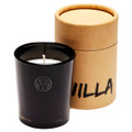 A black glass candle with a white wick, packaged in a round brown cardboard container. Features a logo.