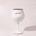 A white Shiraz detachable wine glass with a black interior and a stand, featuring a logo.