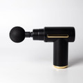 A black massage gun with a gold base and a round black attachment, featuring a sleek design and a logo.