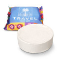 A round white compressed towel in front of colourful packaging featuring a logo.