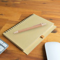 A Savannah Notebook with a spiral binding sits on a wooden surface next to an Eco Matador Pen.