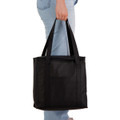 A black cooler bag is being held by a person, featuring sturdy handles and a simple design.