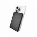 A black solid-state power bank is positioned against a silver smartphone, highlighting its sleek design and portable size.