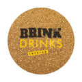 A round cork coaster with a textured golden surface and a logo in black and yellow.