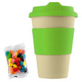 A reusable 12oz bamboo coffee cup in cream with a bright green lid and sleeve, accompanied by a pack of colourful jelly beans.
