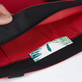 A red tote bag with a black trim, featuring an interior pocket and a decorative card inside.