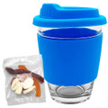 A reusable coffee cup with a blue silicone sleeve and lid, accompanied by a pack of jelly lollies.