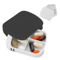 A black and white pill box with compartments containing various tablets and capsules, alongside a separate lid.