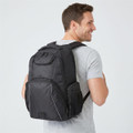 A black laptop backpack with multiple compartments, worn on the back of a person smiling. It features a logo.