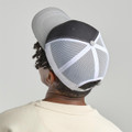 A grey and black trucker cap featuring a mesh back and a button closure at the top.