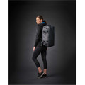 A woman in athletic wear stands sideways, carrying a grey Equinox 30 duffel bag with a logo.