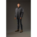 A man stands wearing a grey Men's Tradesmith Jacket, styled with fitted jeans and tan boots. The background is neutral.