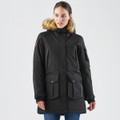 A black women's parka jacket featuring a fur-lined hood and multiple pockets. The model is wearing it in a neutral setting.