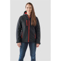 A woman wearing a black and red insulated softshell jacket with a hood and multiple zip pockets.