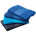 A set of four beach towels in varying shades of blue, stacked neatly. One towel is dark navy, another is light blue, and the third is teal.