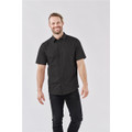 A short-sleeved black button-up shirt worn by a smiling man, featuring a simple design and a logo on the chest.