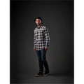 A man stands wearing a black and white checked button-up shirt, paired with jeans and casual shoes.