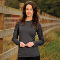 A woman models a long-sleeve, charcoal grey tee with a simple design, set against a natural outdoor backdrop.