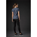 A woman wearing a navy blue crew neck tee paired with black leggings, standing against a dark background.
