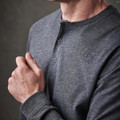 A grey long-sleeve Henley shirt with a two-button placket and fitted sleeves. It features a subtle logo.