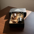 A stainless steel wine glass gift set in a black box, featuring two glasses nestled in straw.