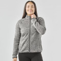 A women's full zip fleece jacket in grey, featuring a high collar and a fitted design. It has a logo on it.