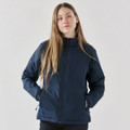 A woman wearing a navy blue thermal jacket with a zippered front and side pockets, featuring a logo.