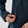 A navy women's softshell jacket featuring a zippered pocket. The jacket has a close-up view of the hand and zipper detail.