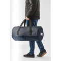 A person carrying a navy waterproof duffel bag with black straps and a branding logo.
