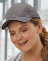A grey cap with a curved brim, featuring a logo, worn by a woman indoors.