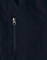 A close-up of a navy softshell jacket featuring a zippered pocket. The fabric appears smooth and durable.