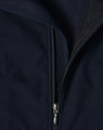 A close-up of a navy softshell vest featuring a zippered front and a fleece lining. The vest has a logo on it.