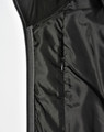 A black quilted jacket featuring a heather sleeve and a zippered pocket on the interior.