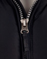 A heavy quilted black jacket with a silver zip featuring the brand logo, showcasing a close-up of the zipper area.