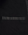 A close-up of a black long line stadium jacket featuring a sleek design and a pocket. The jacket has a branding logo.