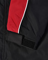 A unisex jacket featuring black fabric with red and white accents and a velcro closure on the sleeve.