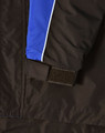 A close-up of a unisex jacket featuring black fabric with blue and white accents and a Velcro detail.