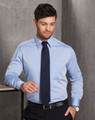 A men's fine chambray long sleeve shirt in light blue, paired with a tie, featuring a chest pocket and a logo.