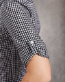 A black and white gingham check roll-up long-sleeve shirt featuring button details on the sleeves and a logo.