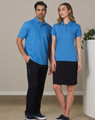 A man and woman standing together, wearing matching blue polo shirts. The man pairs his top with black cargo pants, while the woman wears a black skirt.