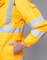 A bright yellow safety jacket with reflective stripes, featuring a pocket and adjustable cuffs. It has a logo.