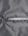 A close-up of a grey quilted fabric with a zip closure, highlighting the texture and stitching details.