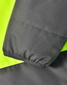 A close-up of a two-tone safety jacket featuring fluorescent yellow and charcoal grey fabric. It has a textured finish and elastic cuffs.