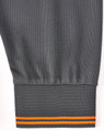 A grey long-sleeve polo shirt featuring segmented detailing with an orange stripe at the cuff. It has a logo on the garment.