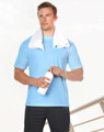 A man stands holding a white drink bottle, wearing a light blue short sleeve tee and a towel draped around his neck.